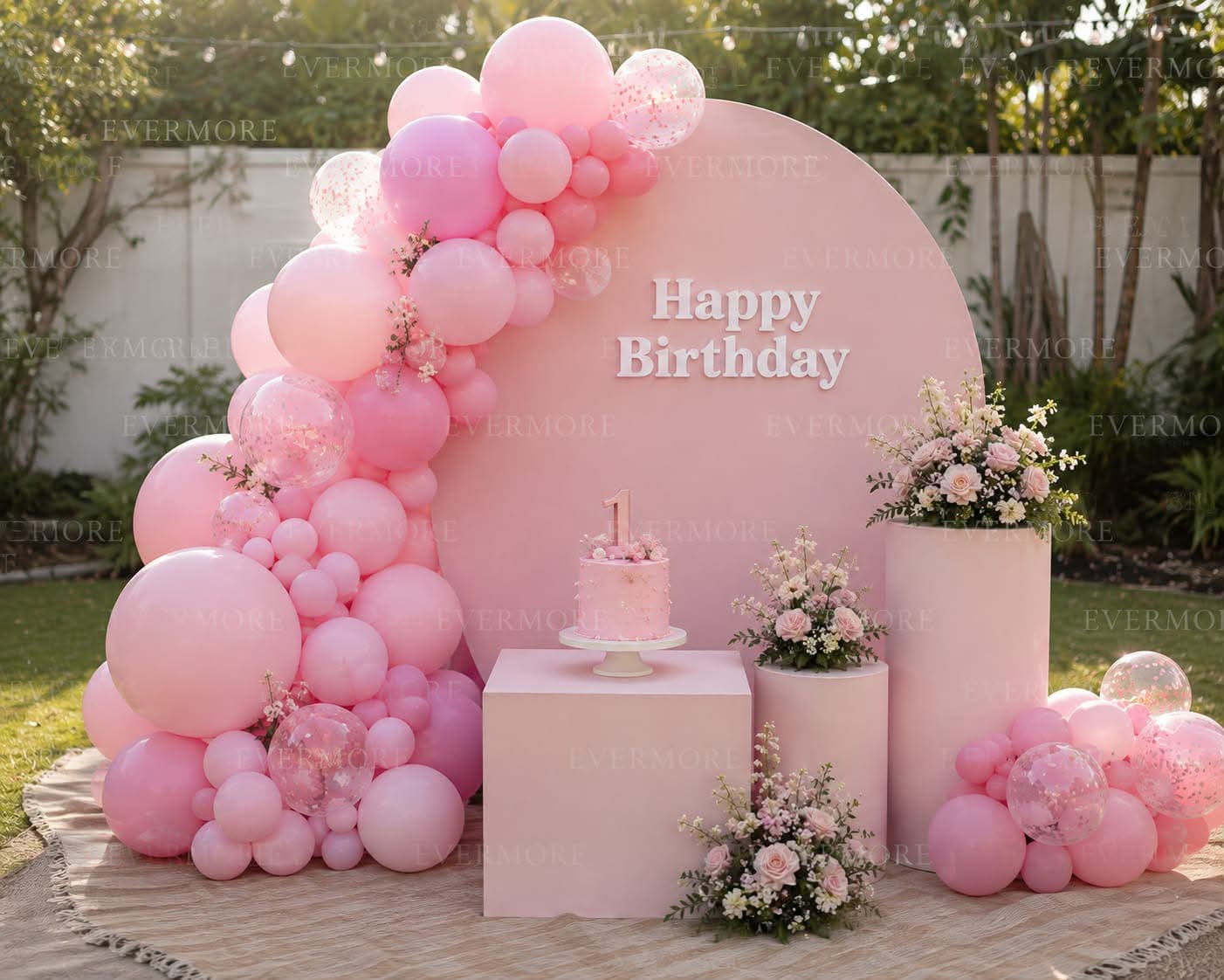 Outdoor first birthday setup with a pink circular backdrop and balloon garland